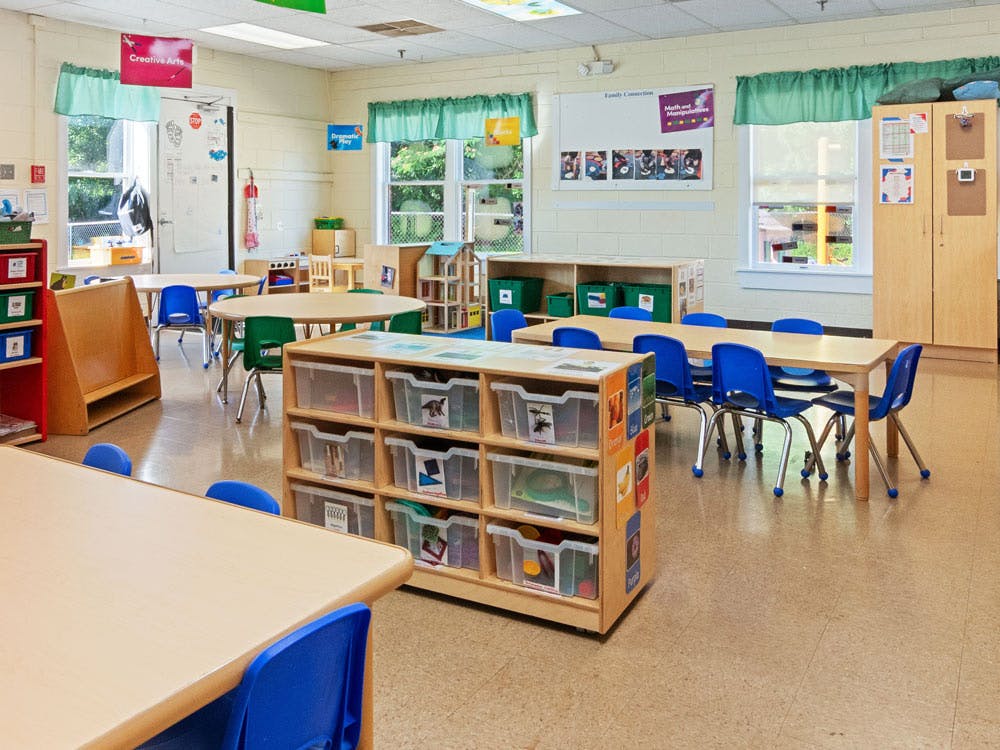 Classroom with small tables, chairs, and storage bins