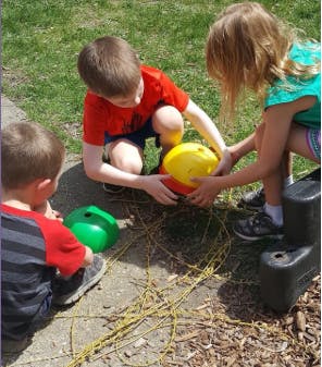 Three children playing with colorful plastic bowls outdoors