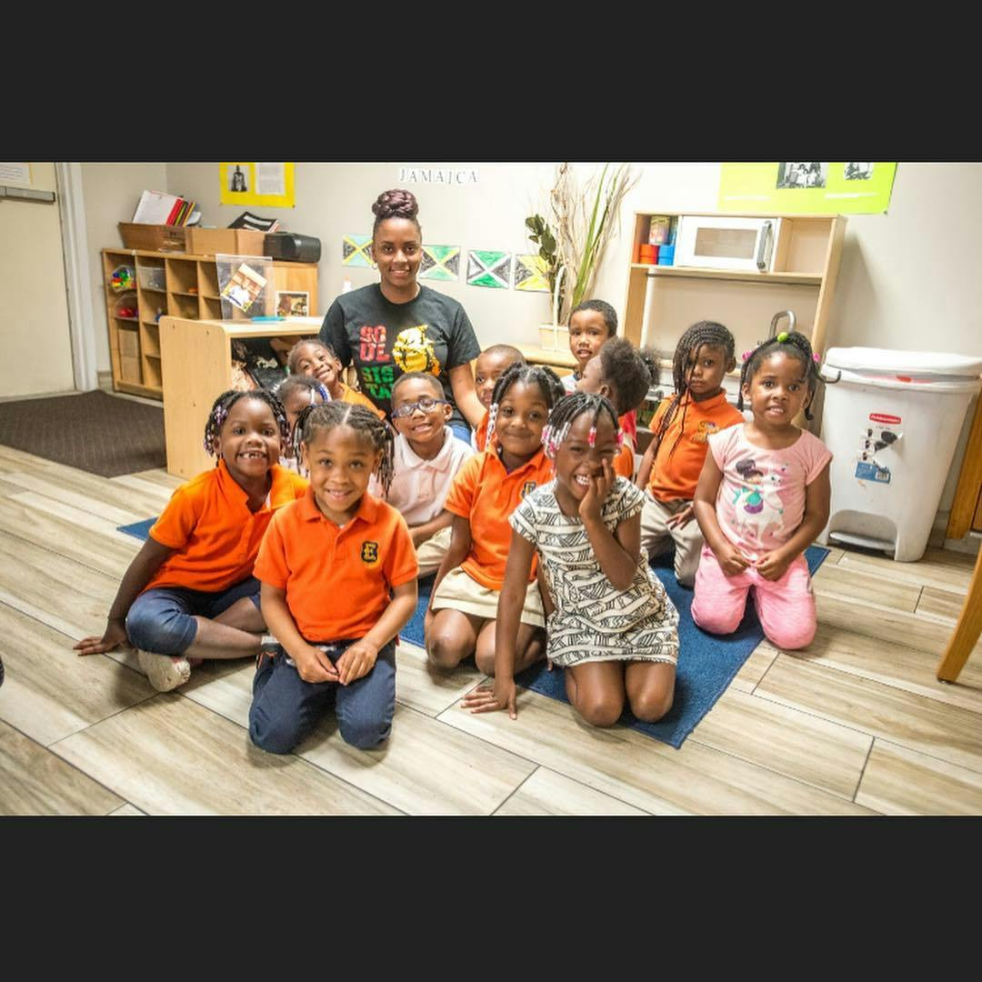 Adult and group of children posing in a classroom