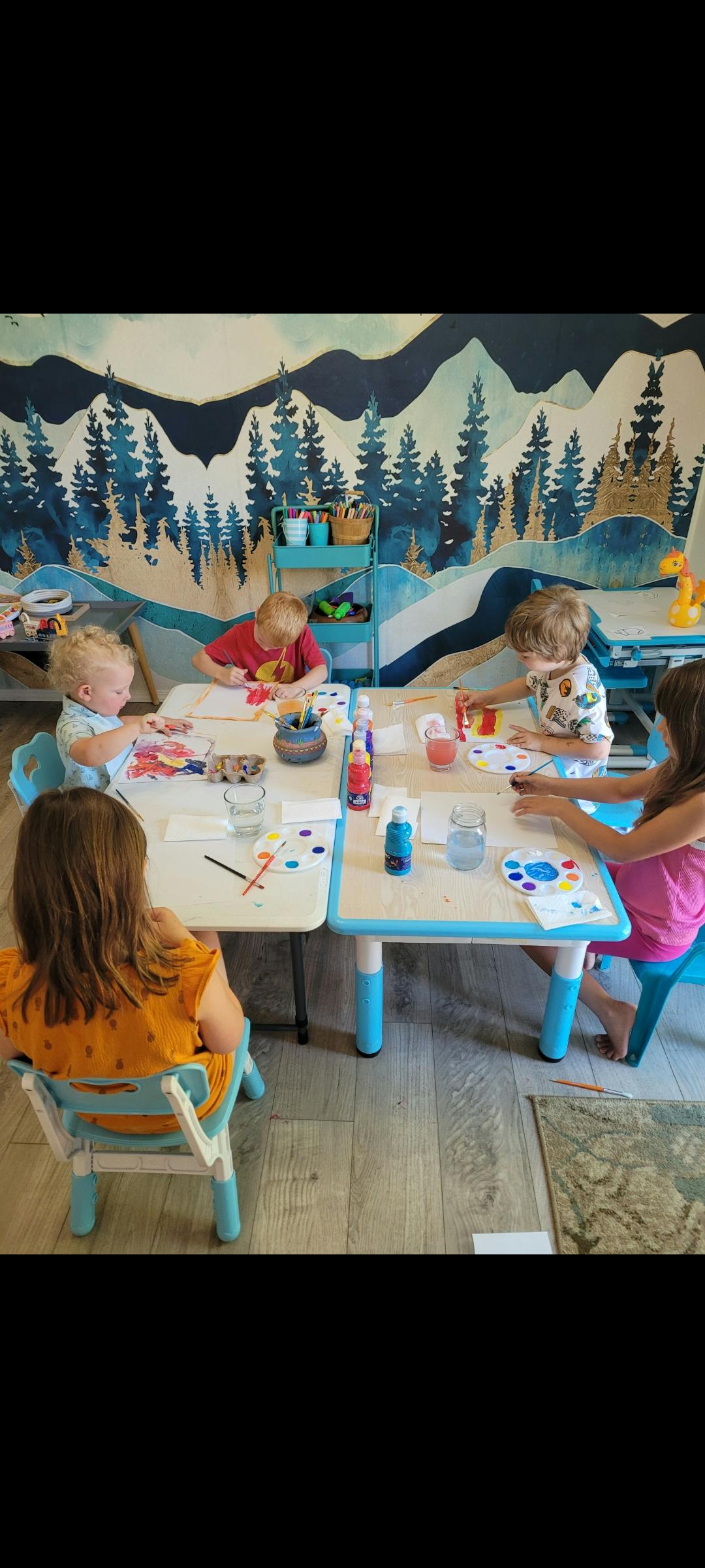 Children painting at tables in a classroom
