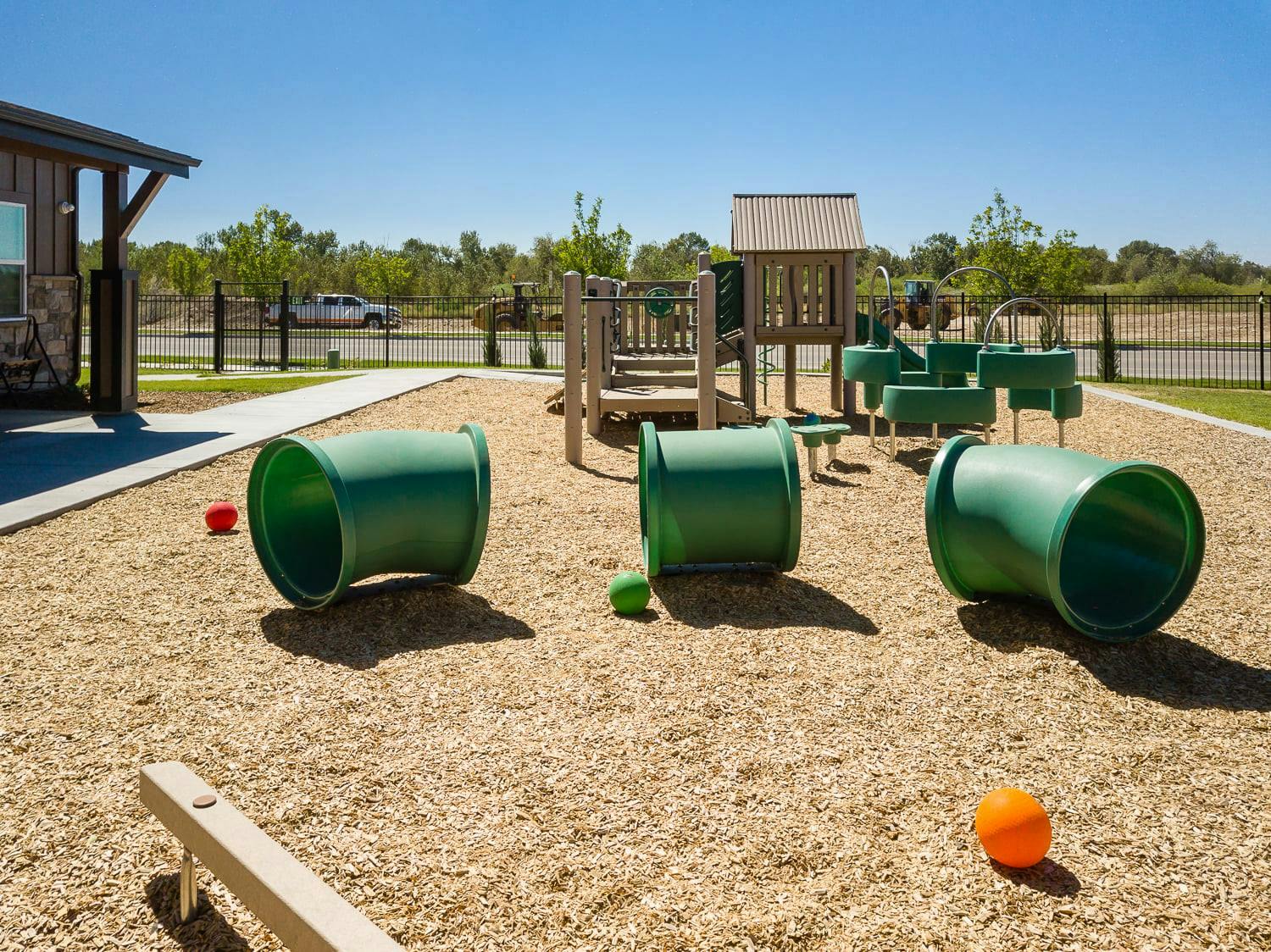 Outdoor playground with green tunnels and wooden play structure