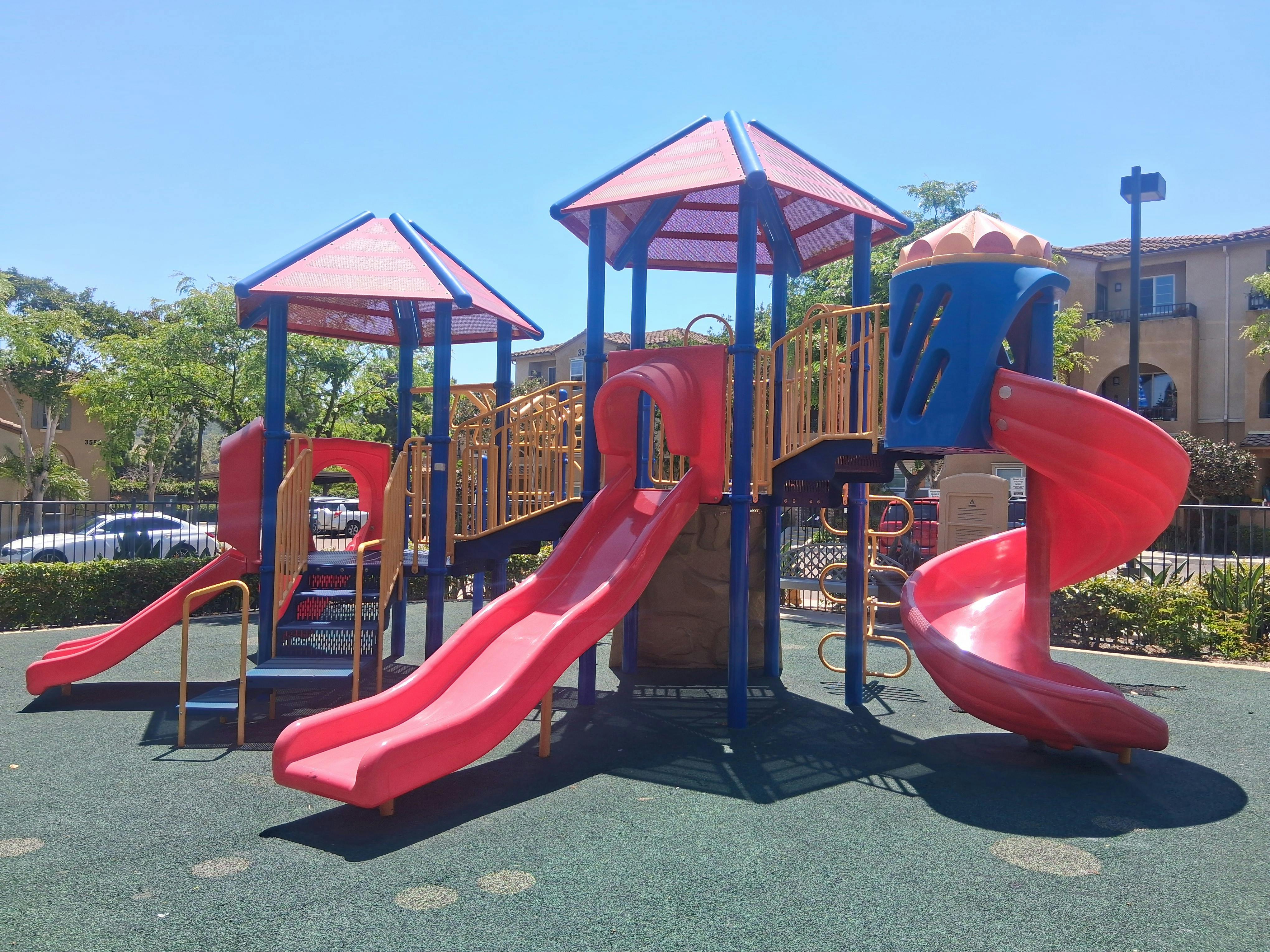 A red and blue children's playground with slides and climbing structures