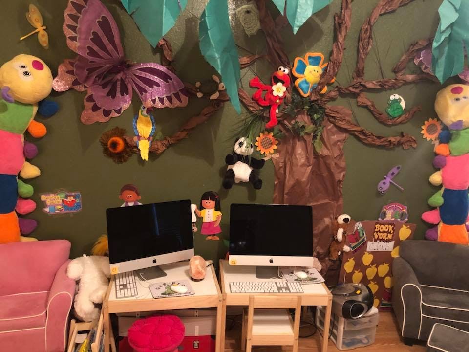 Two computer workstations in a room with a colorful, decorated wall