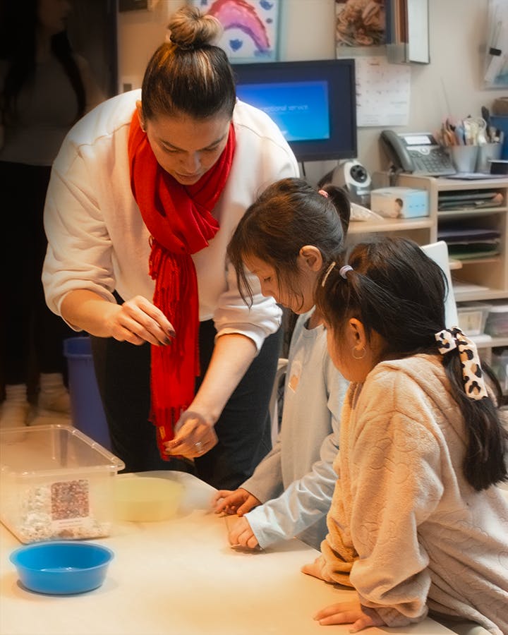 Person helping two children with a craft project on a table