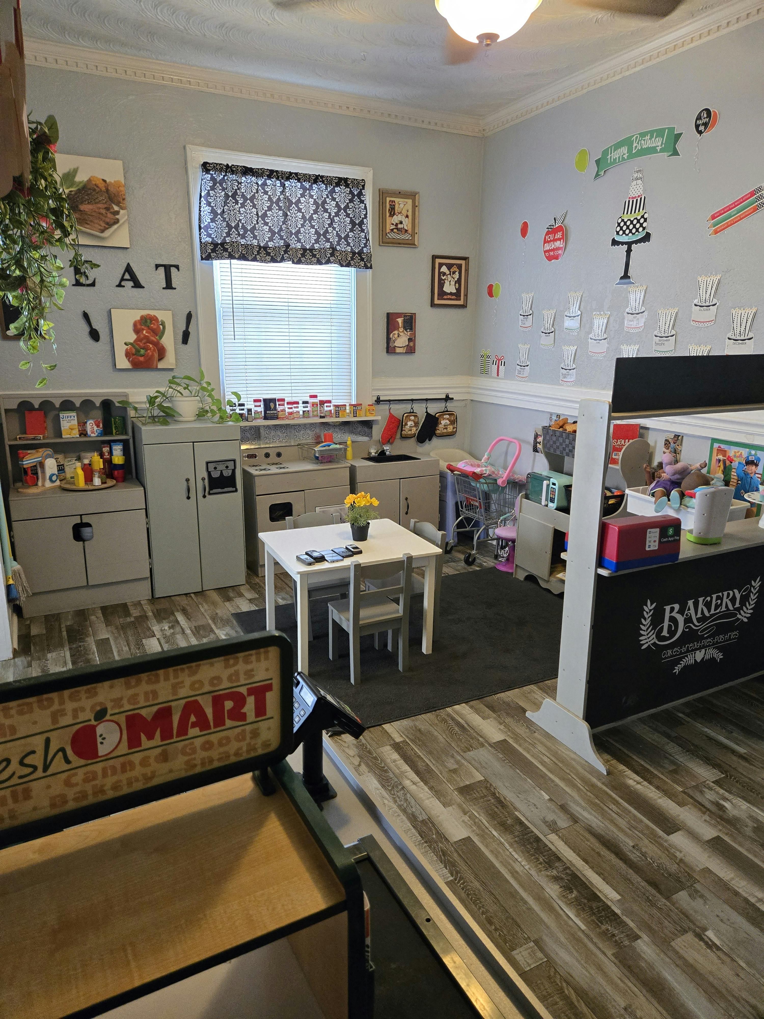 Playroom with toy kitchen, table and chairs, and a Fresh Mart sign