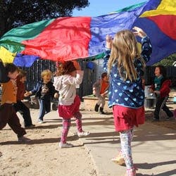 Children playing with a colorful parachute