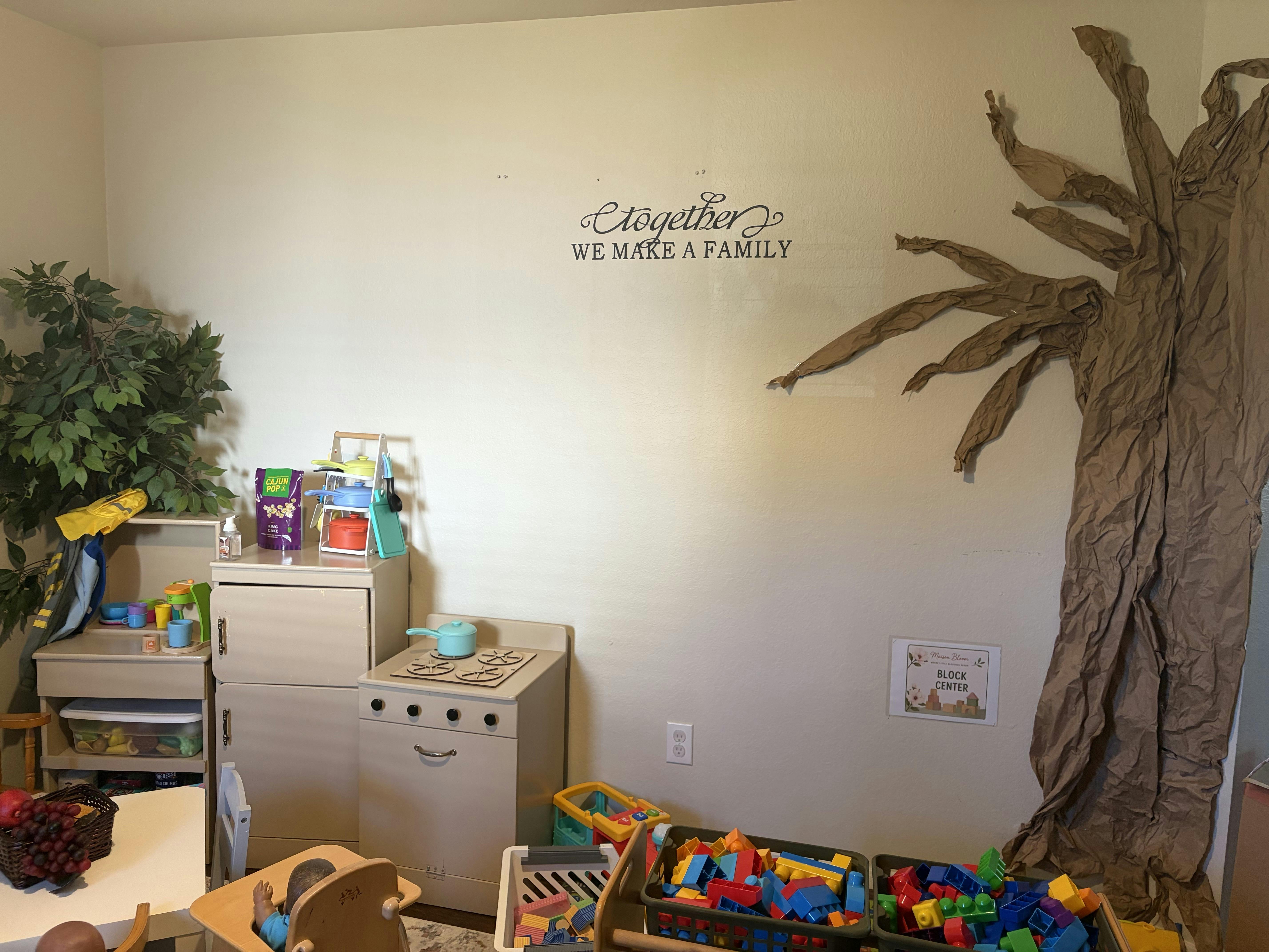Playroom with a toy kitchen and a large paper tree on the wall