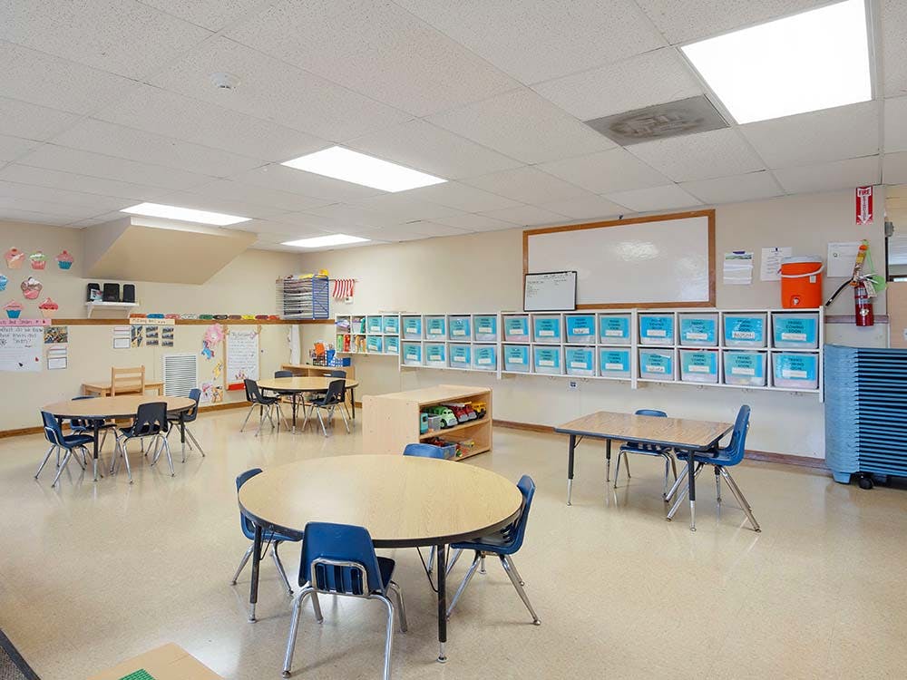 Empty classroom with several round and rectangular tables and chairs