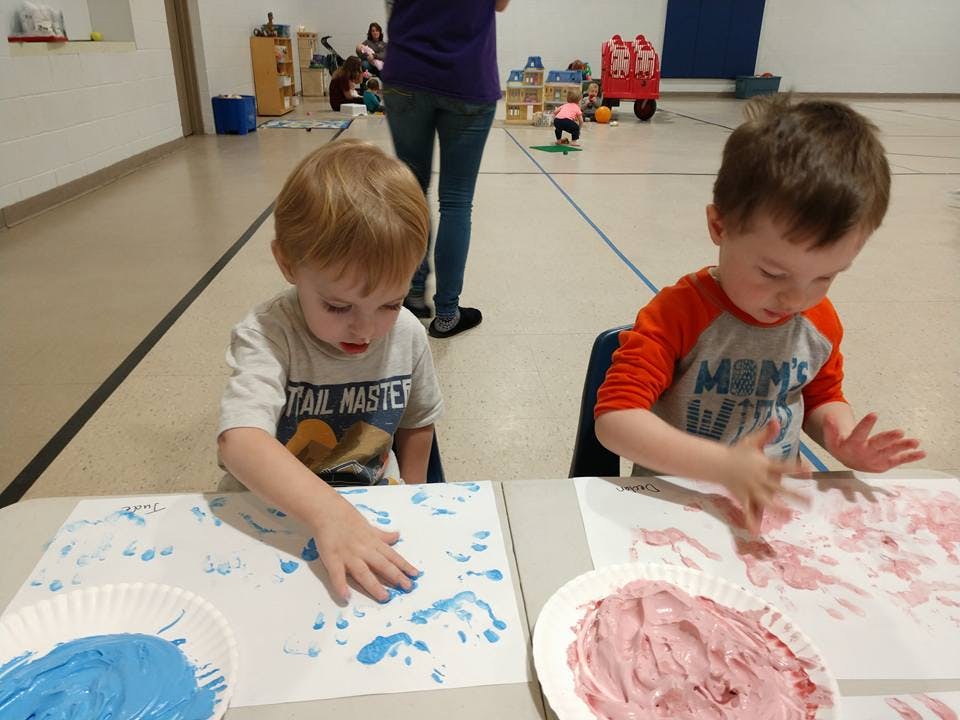 Two children finger painting at a table