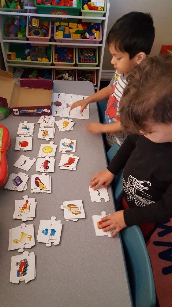 Two children playing with puzzle pieces on a table