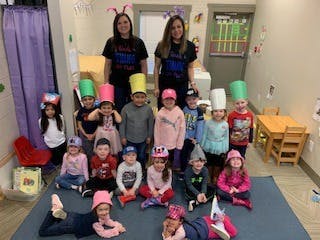 Two adults and multiple children wearing hats