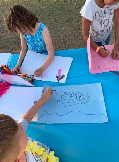 Three children drawing on paper at a table