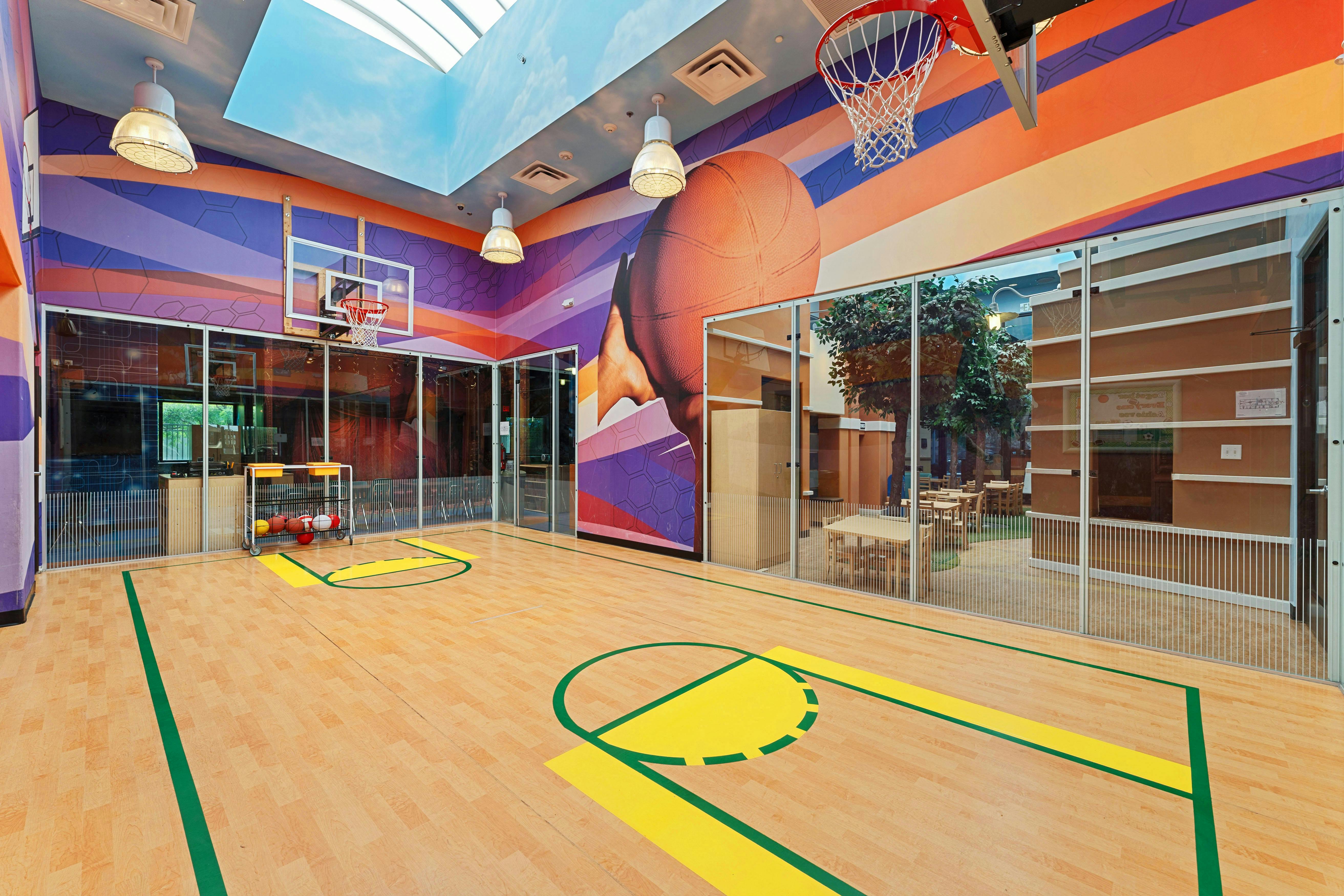 Indoor basketball court with colorful walls and a skylight