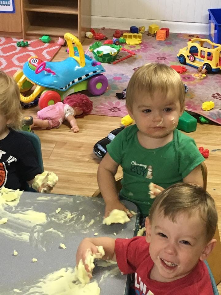 Three children playing with a messy substance at a table