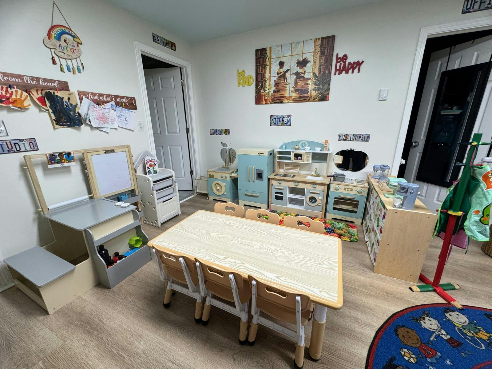 Children's playroom with small table and chairs, easel, and play kitchen area