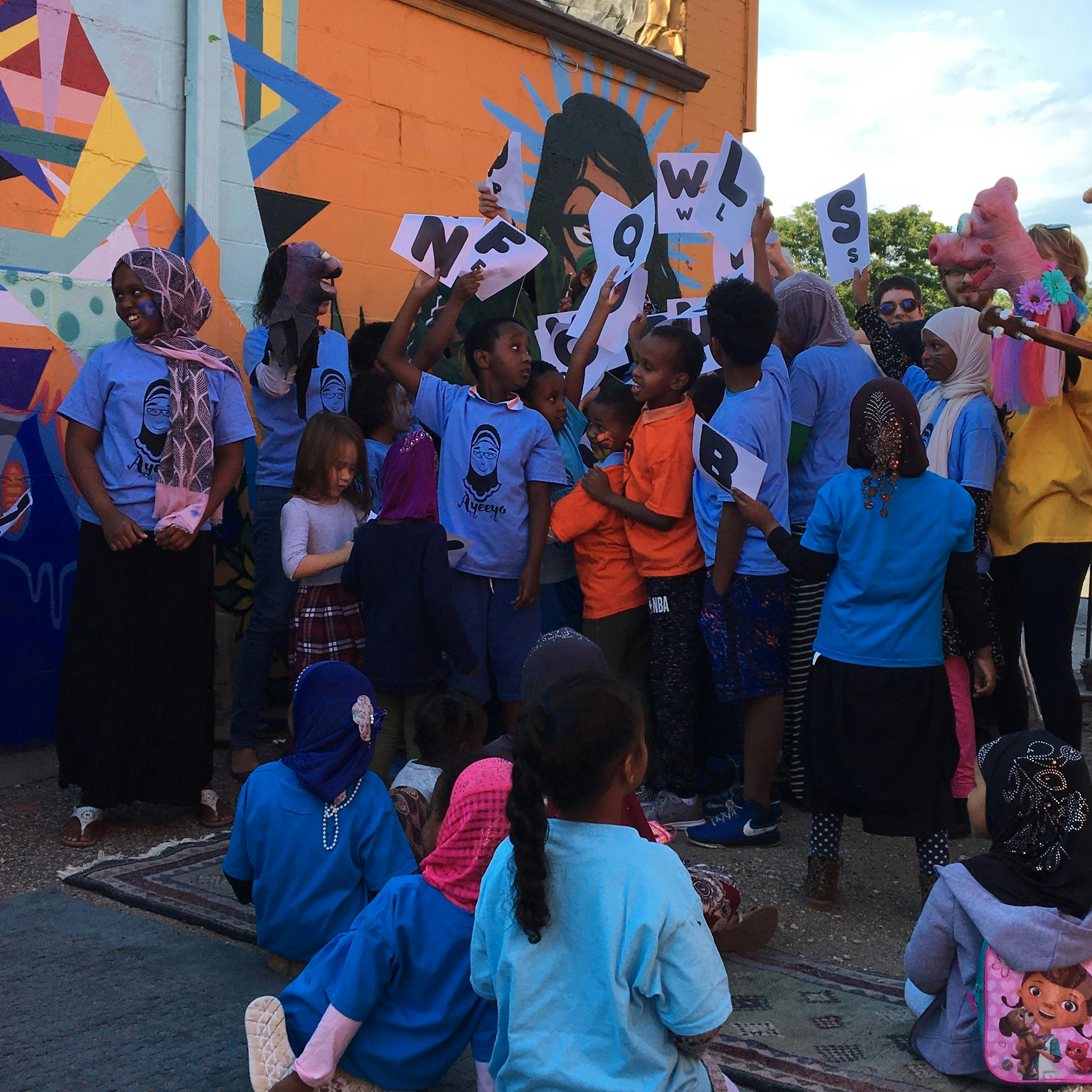 Group of children holding up letters in front of a mural