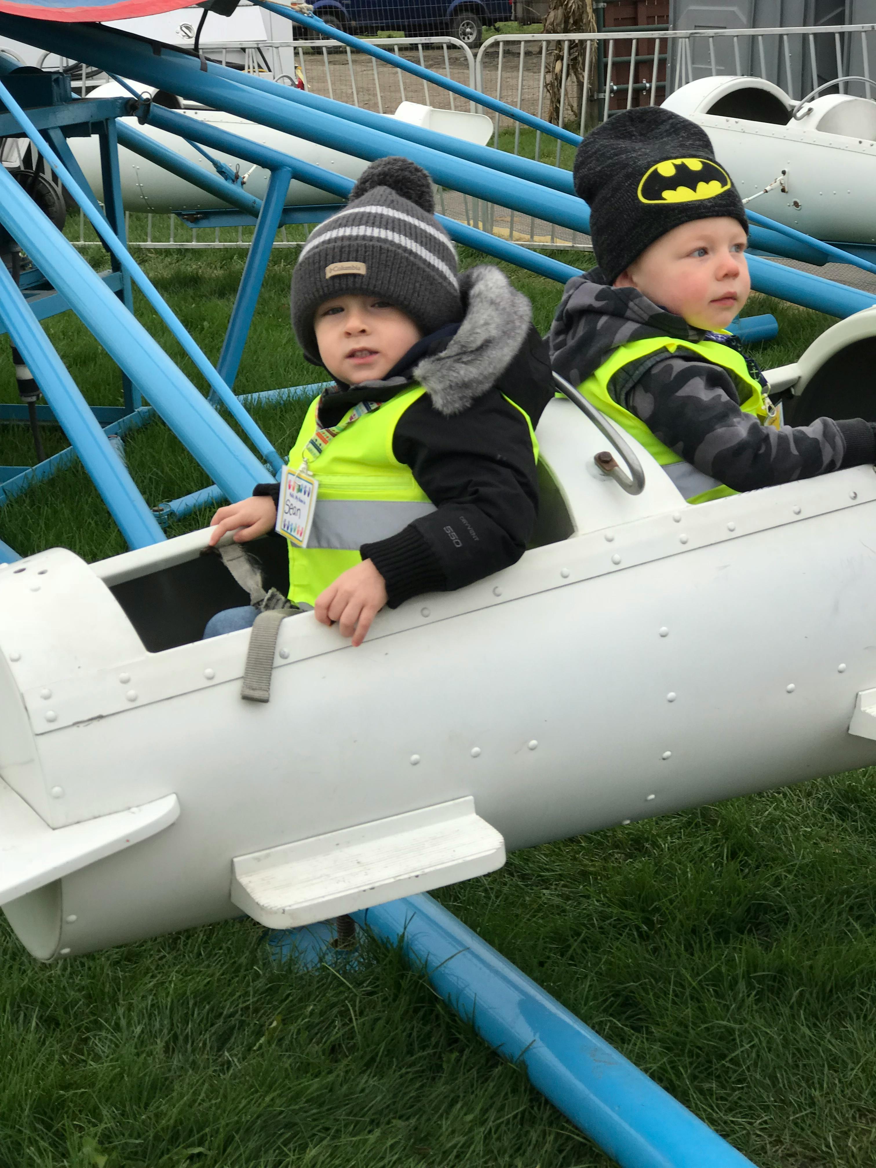 Two children in toy airplanes on a ride