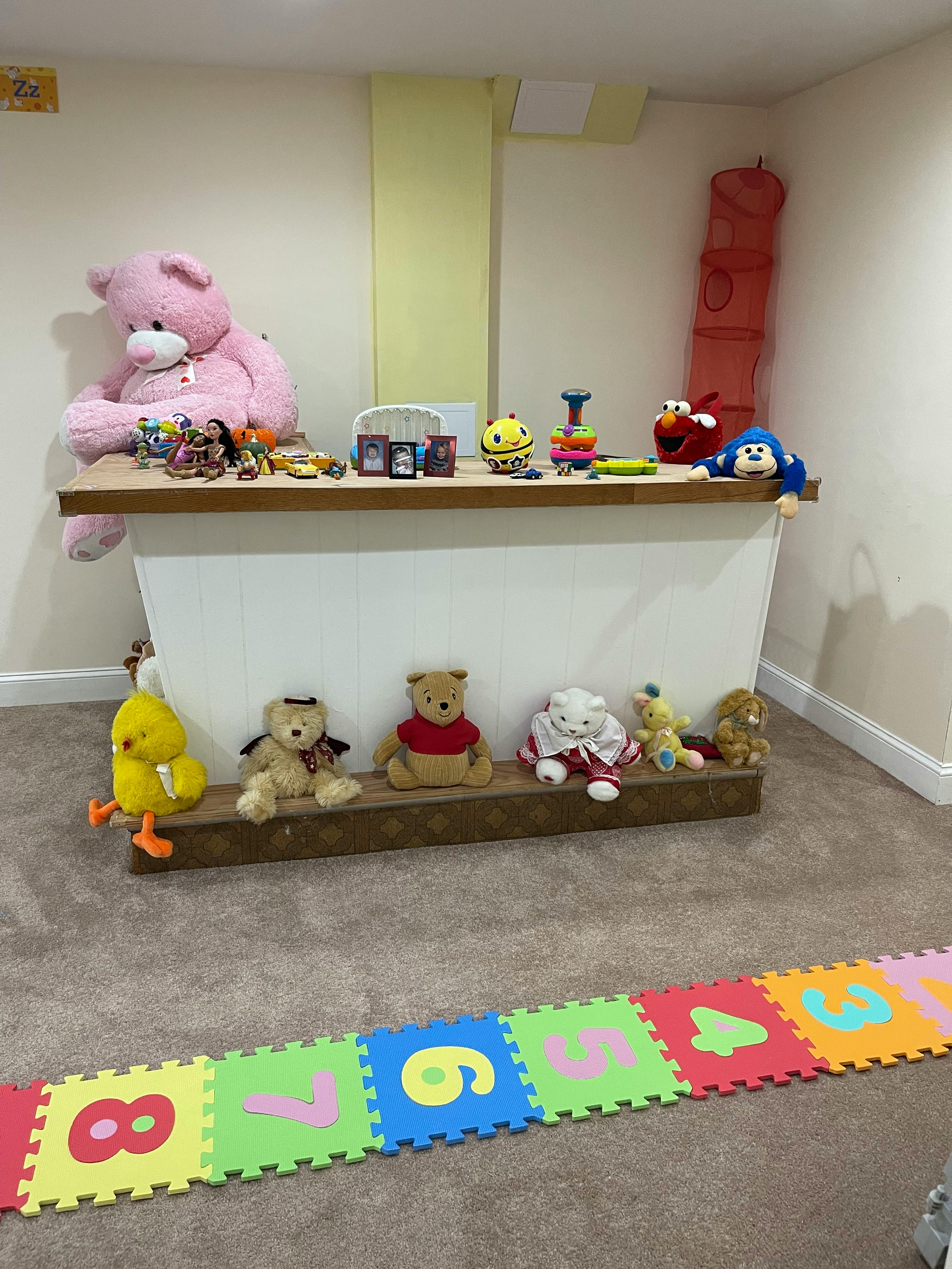 Stuffed animals and toys on shelves with number playmats on the floor