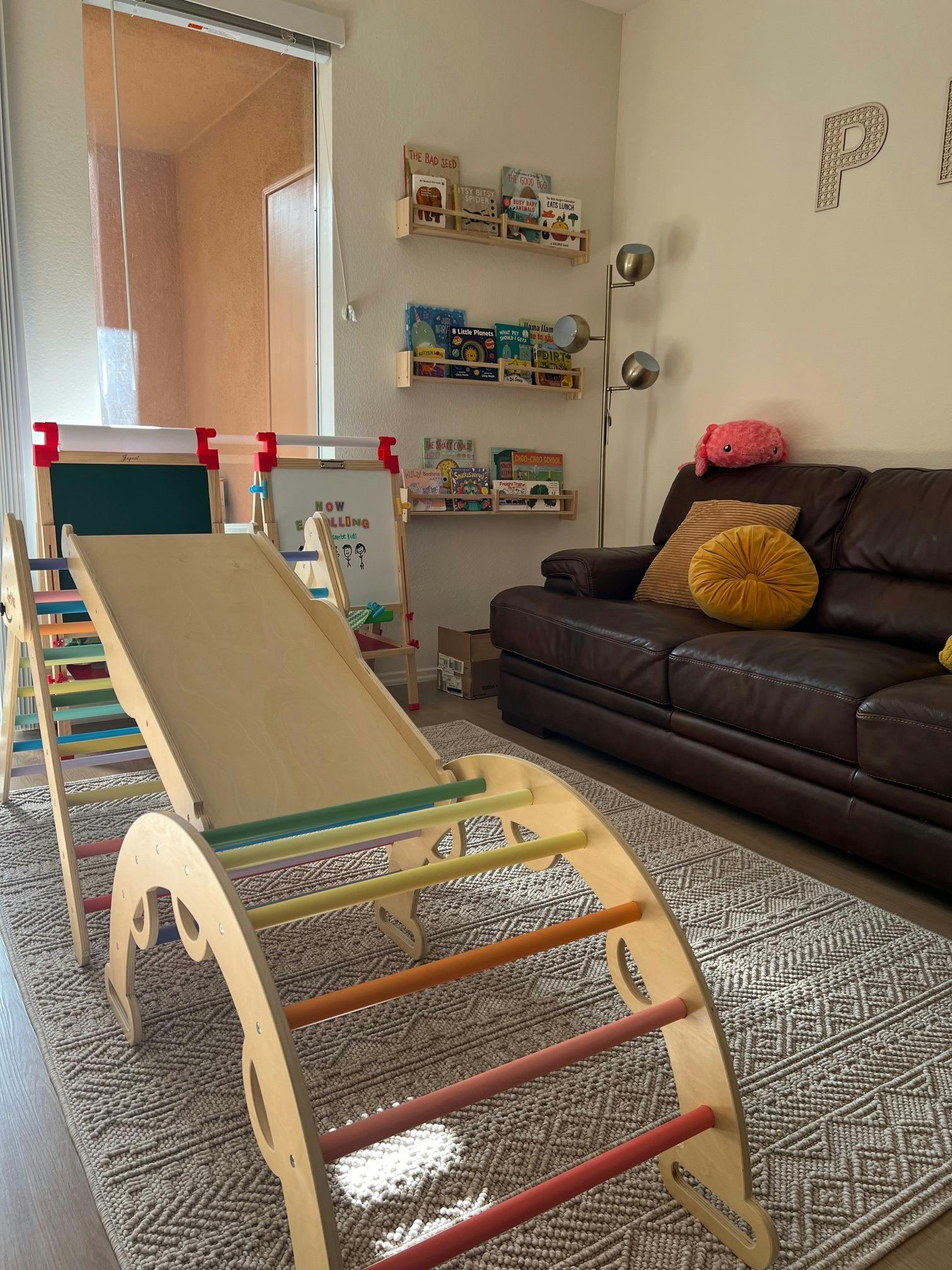 Indoor play area with a wooden slide and climbing arch on a rug