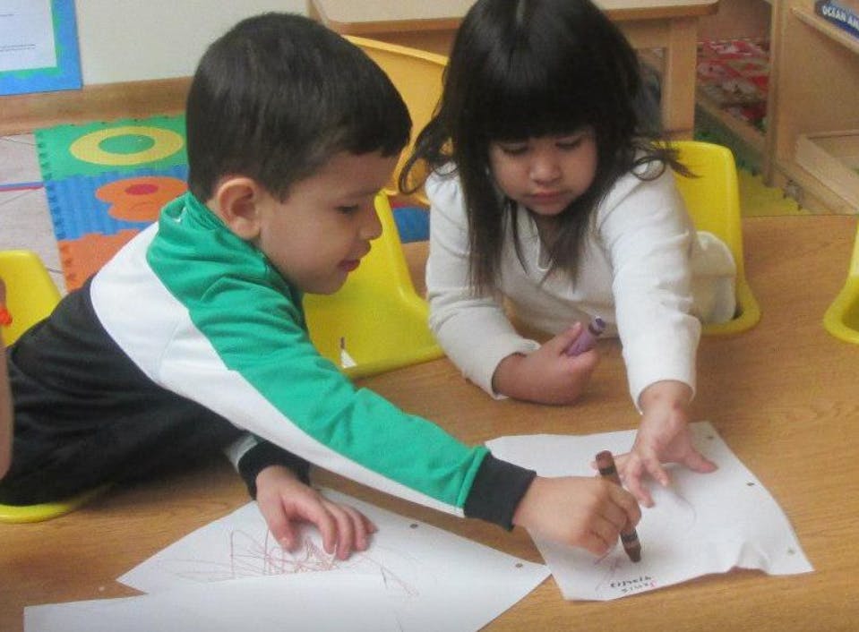 Two children drawing on paper at a table