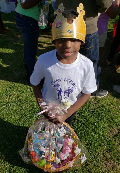 Child wearing a crown and holding a basket of basket of toys