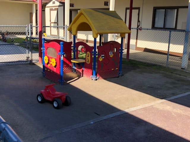 Red and yellow playground structure with a red toy car on the ground