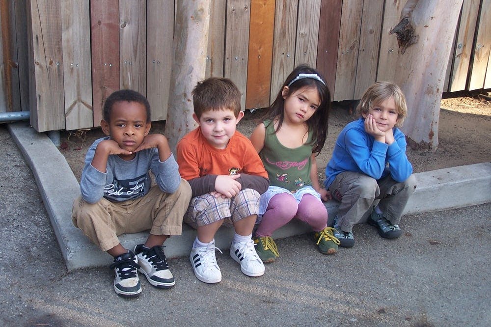 Four children sitting on a curb