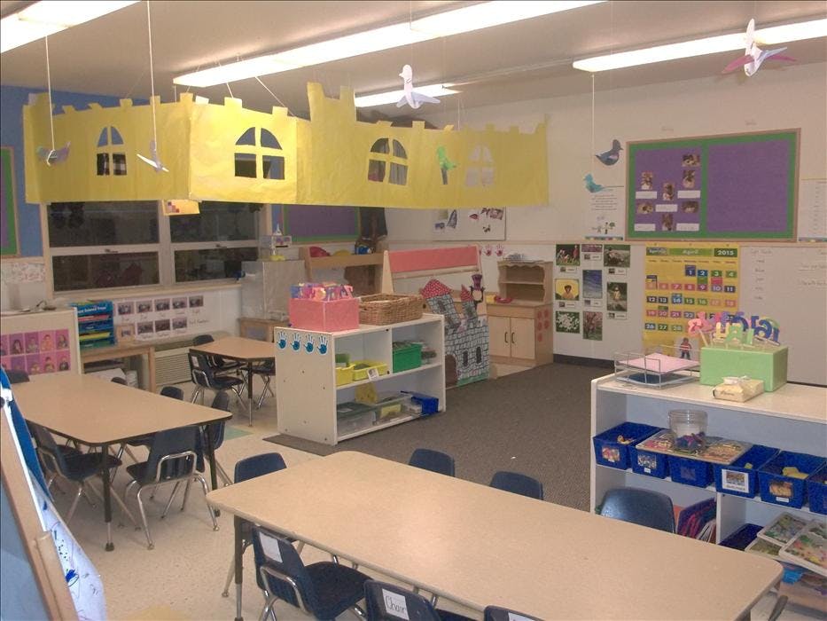 Empty classroom with small tables and chairs, and a yellow paper castle decoration