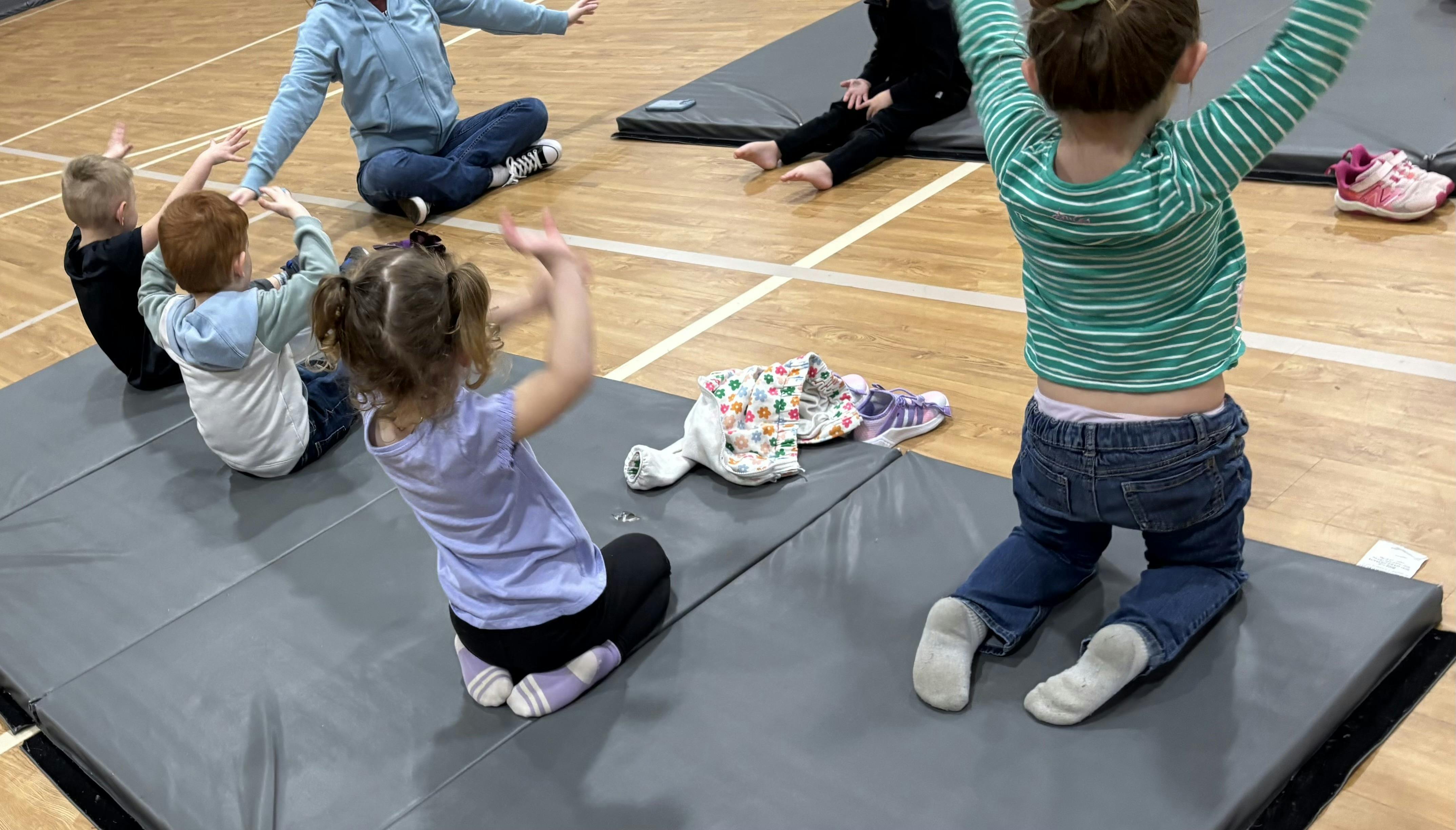 Children and a person doing exercises on mats
