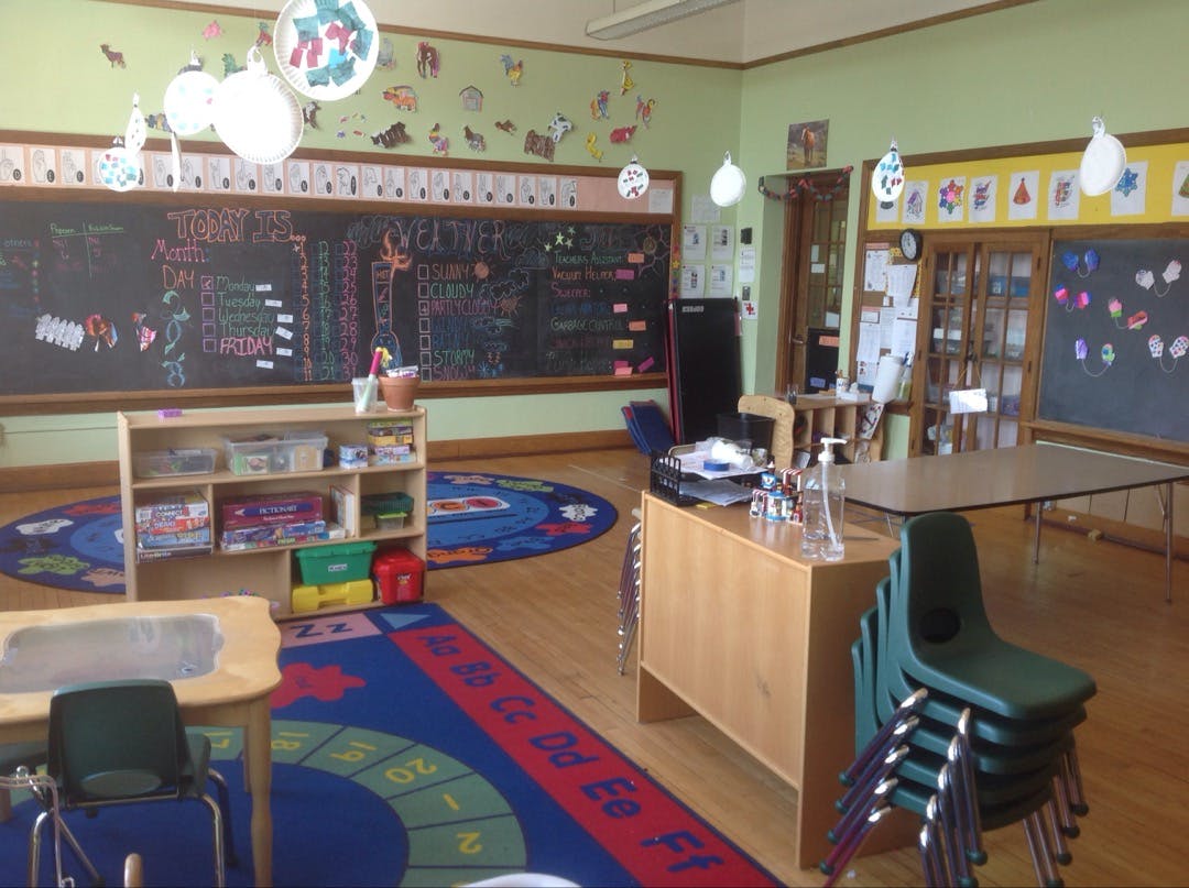 Classroom with chalkboards, colorful rugs, and small tables and chairs