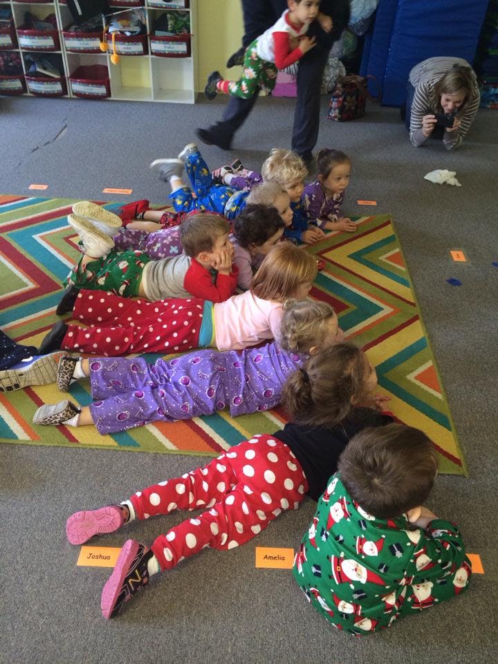 Children lying on a rug and floor, looking forward