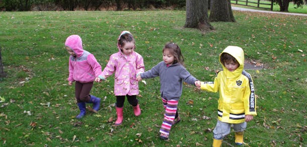Four children holding hands and walking on grass