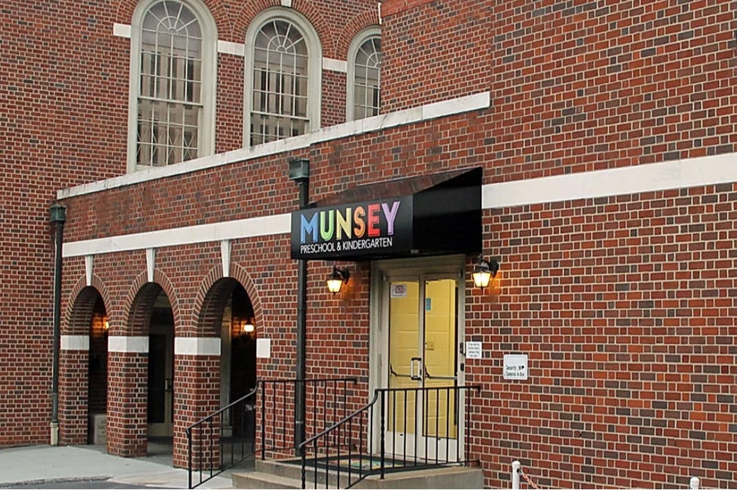 Brick building with arched entrances and a sign that reads "MUNSEY preschool & kindergarten"