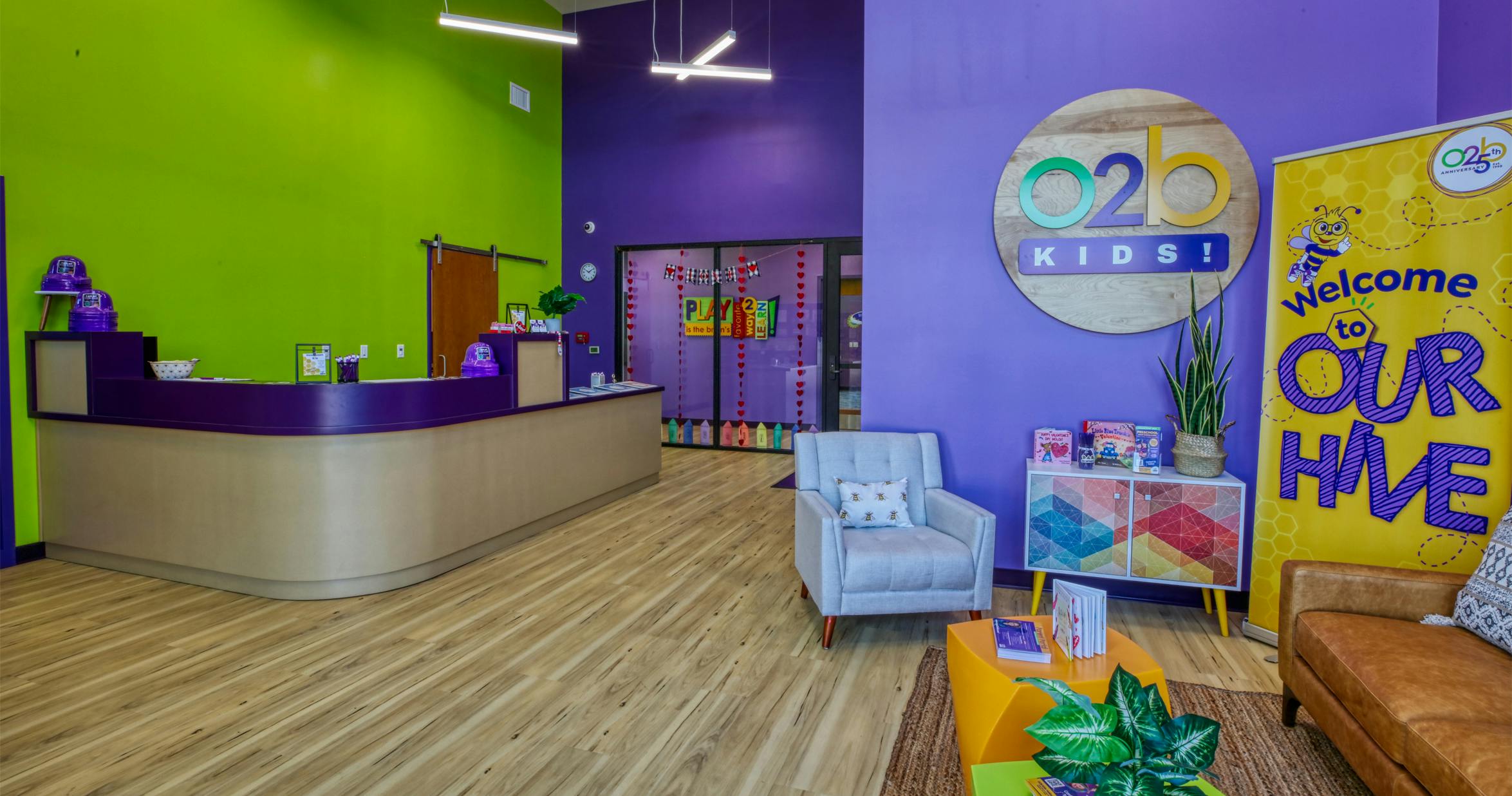 Reception area with a purple counter, colorful walls, and a sign for O2B Kids