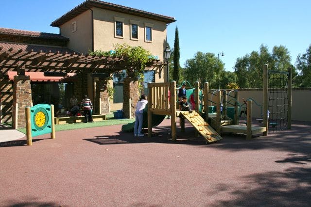 Children playing on a playground structure outside a building
