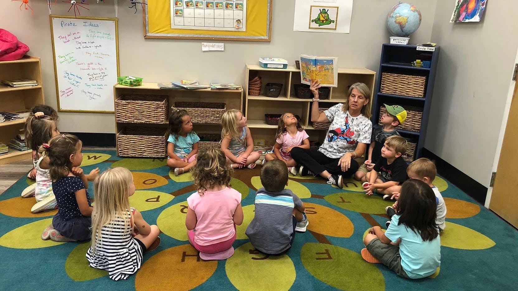 Adult reading a book to a group of children sitting on a rug