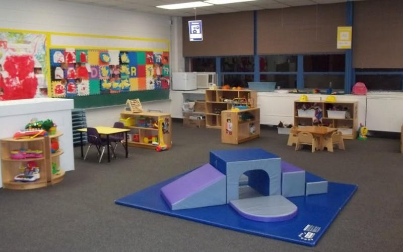 Classroom with child-sized furniture and colorful play mats on the floor