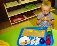 Child working with colorful objects on a tray