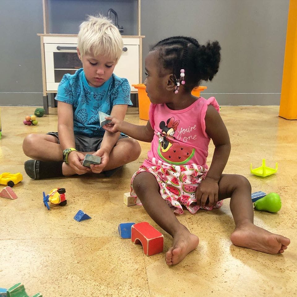Two children sitting on the floor playing with blocks