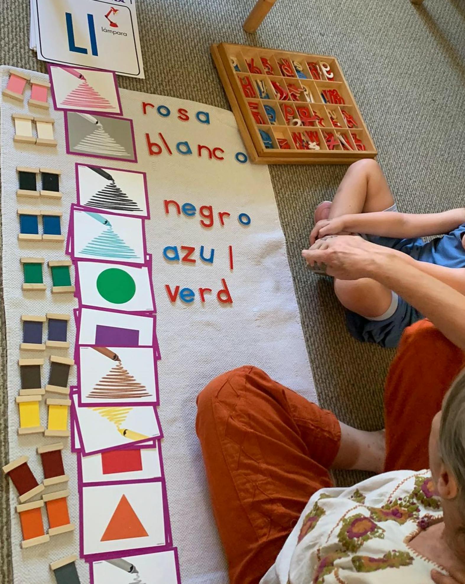 People on floor with educational materials, color cards, and letter tiles