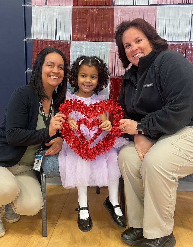 Two people and a child holding a heart-shaped decoration