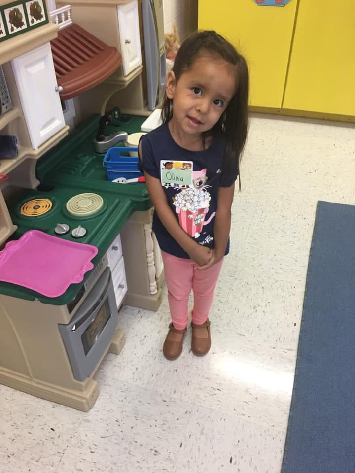 Child standing next to a toy kitchen set