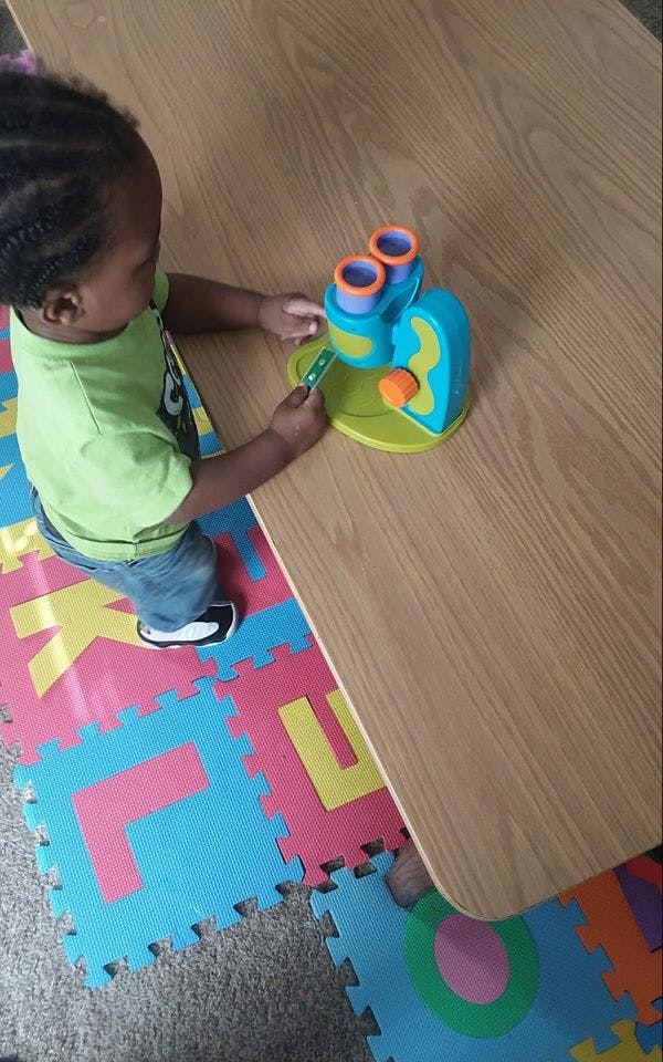 Child playing with a toy microscope on a table