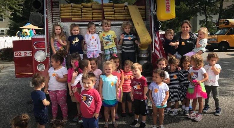 Group of children and an adult standing in front of a fire truck