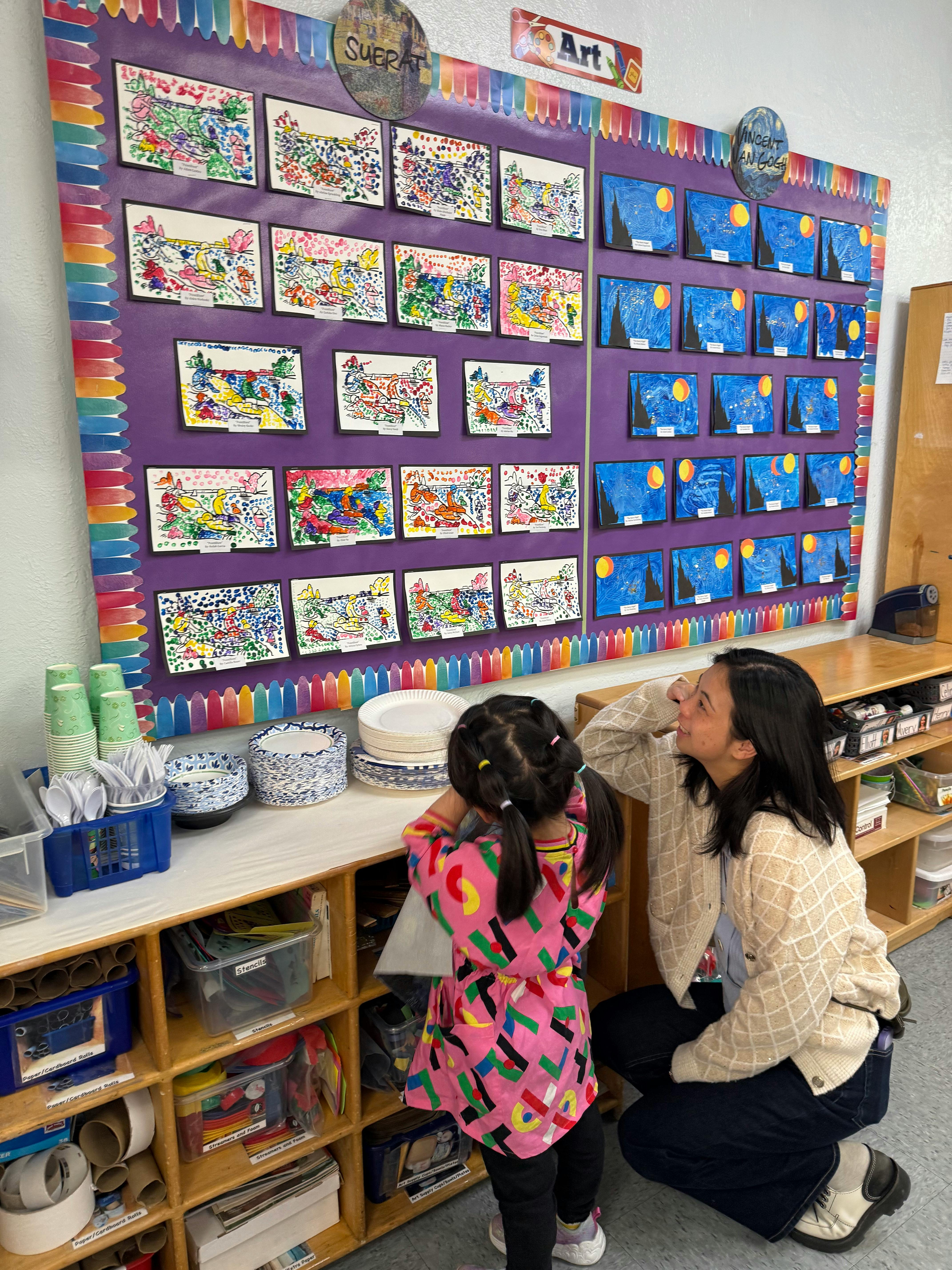 Adult and child looking at artwork on a classroom display board