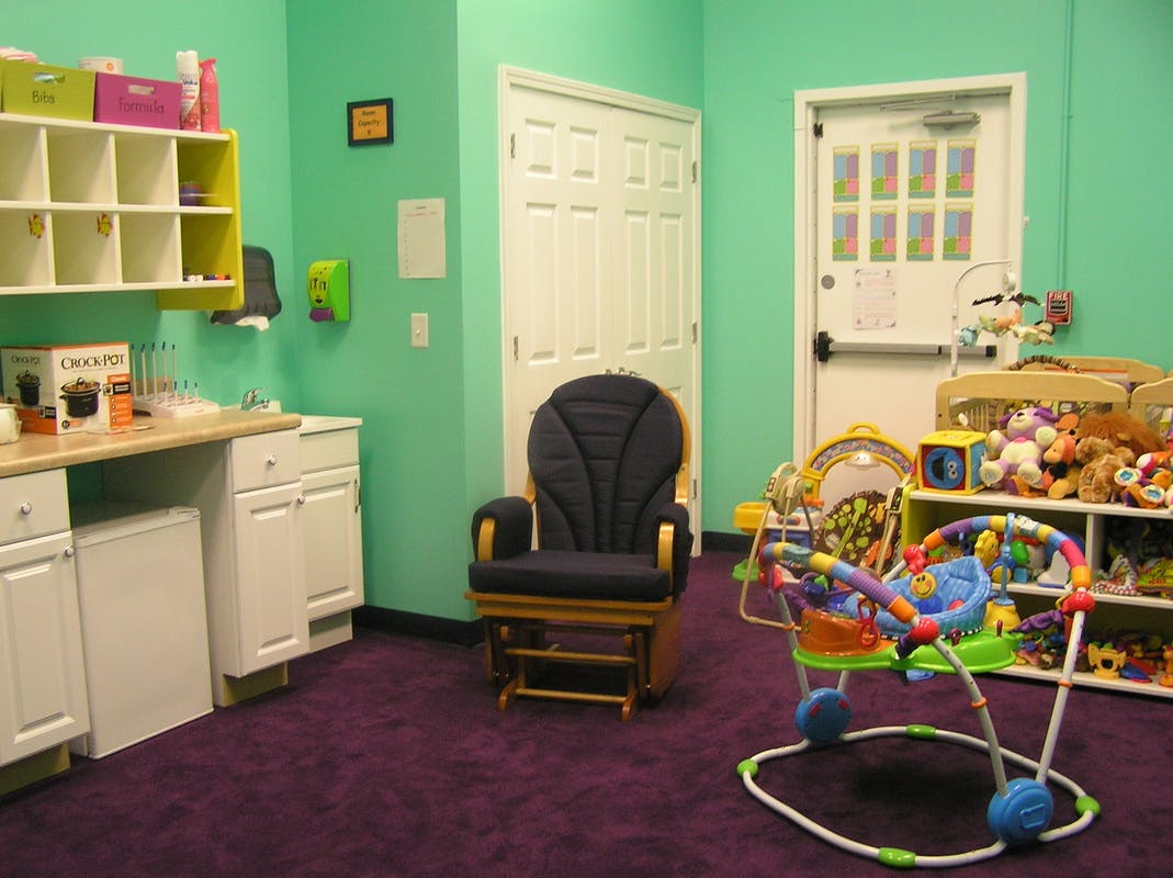 Childcare room with a rocking chair, baby bouncer, and shelves