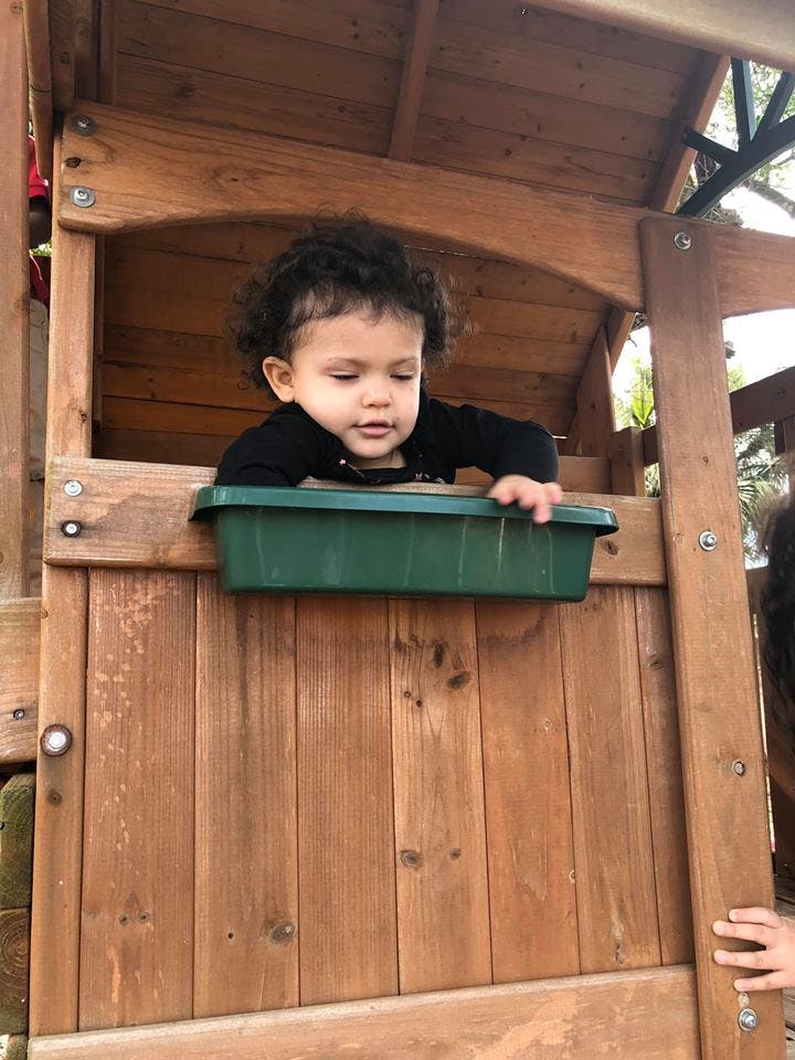 Child looking out from a wooden playhouse window