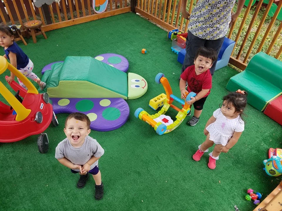 Three children playing with toys on green turf