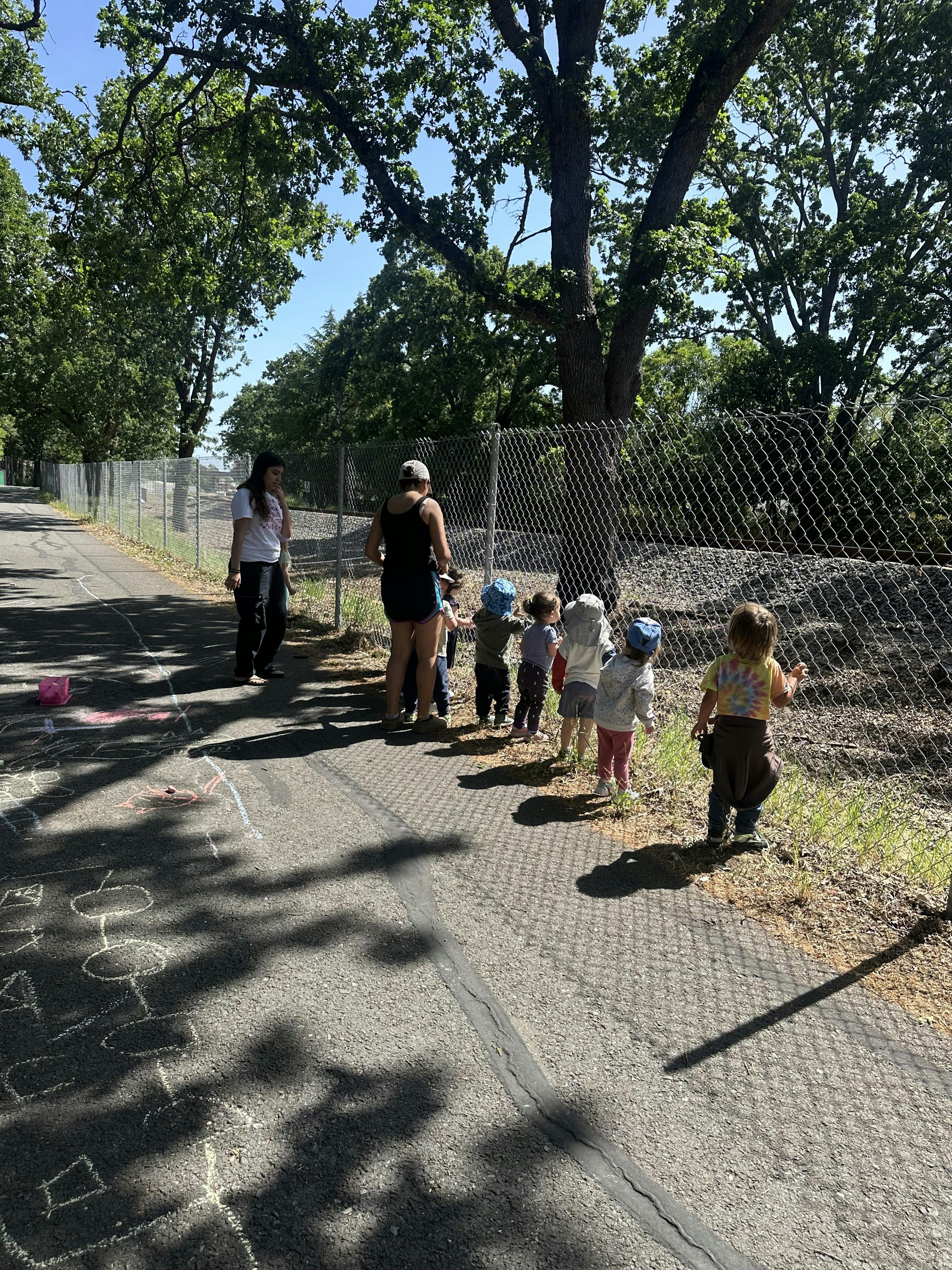 Two people and several children walking along a fence
