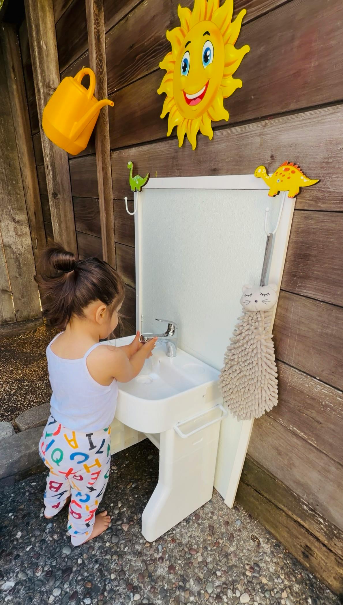 Child washing hands at a small outdoor sink
